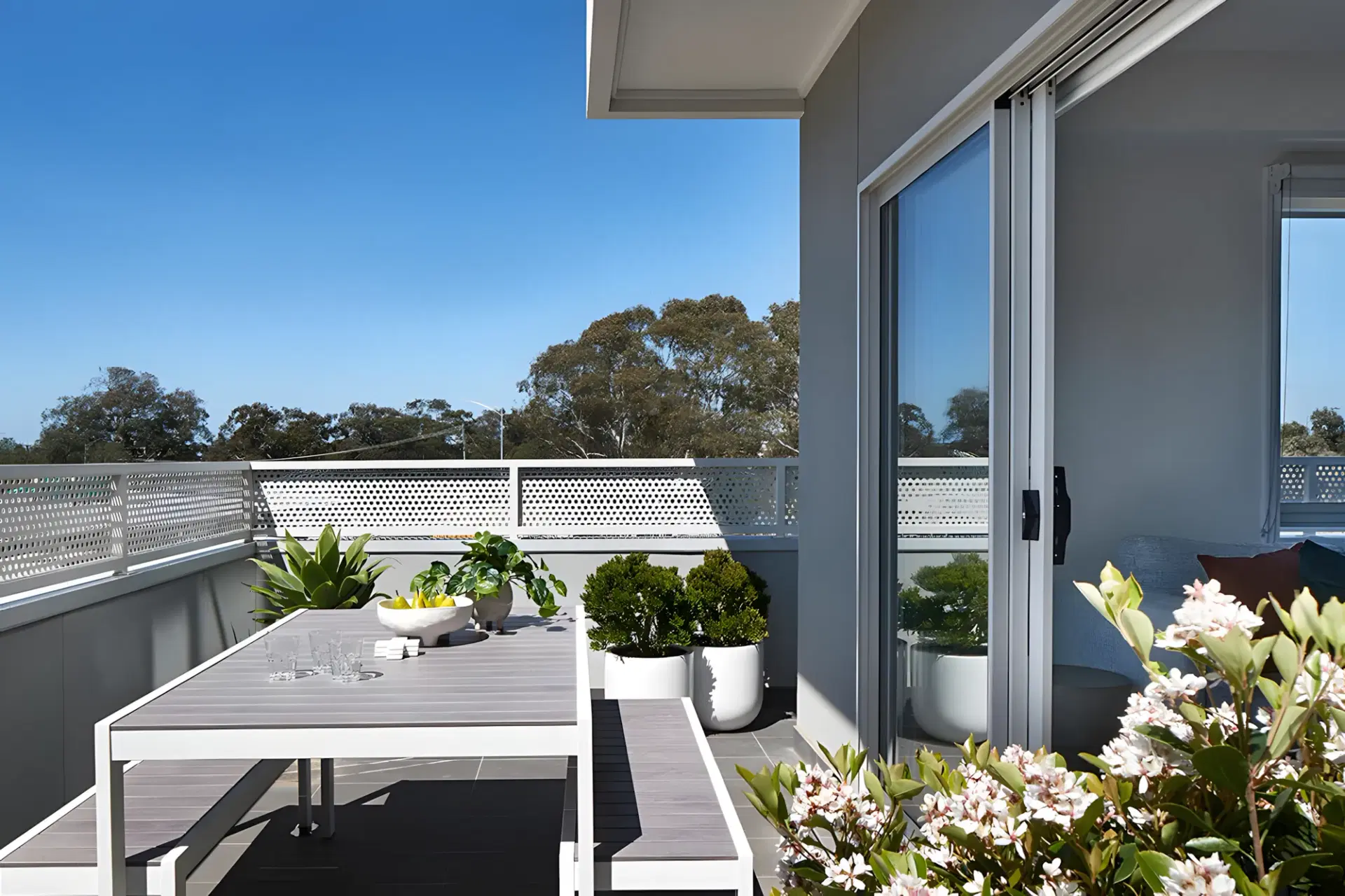 Private balcony with an outdoor table and planting, looking over neighbouring rooftops