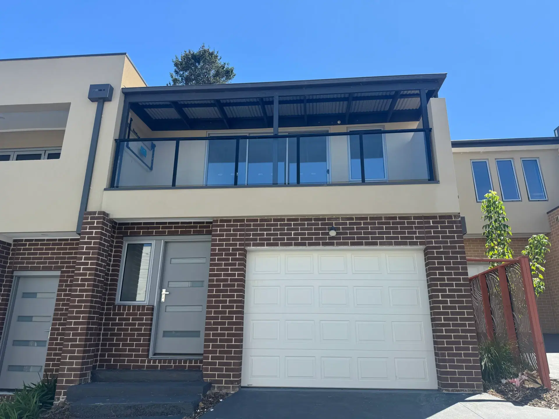 Facade of a Mooroolbark town home in brick and render with a balcony above the garage