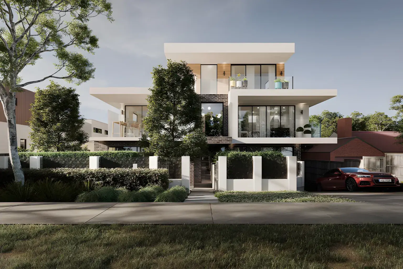 Completed contemporary residence with white rendered forms above a clipped hedge and lawn
