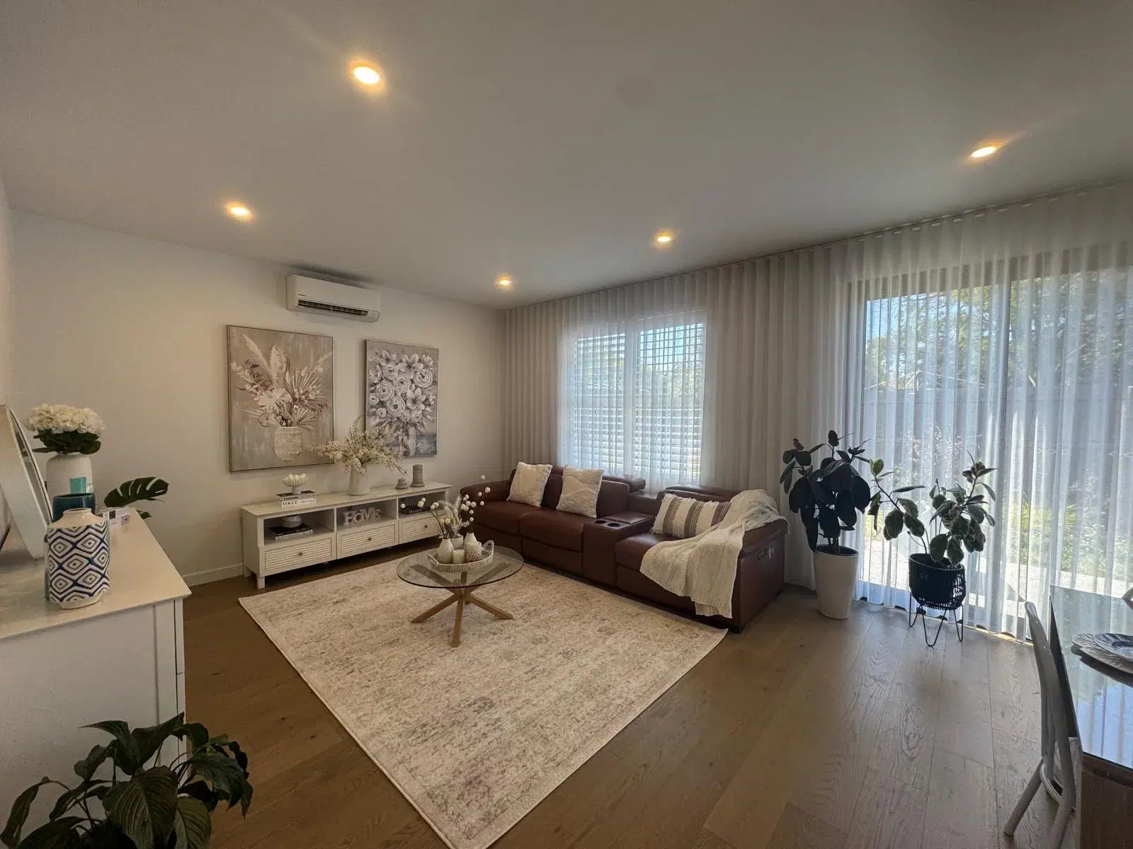 Living room on Chapel Drive, Wantirna South, with a leather sofa, oak flooring and sheer curtains
