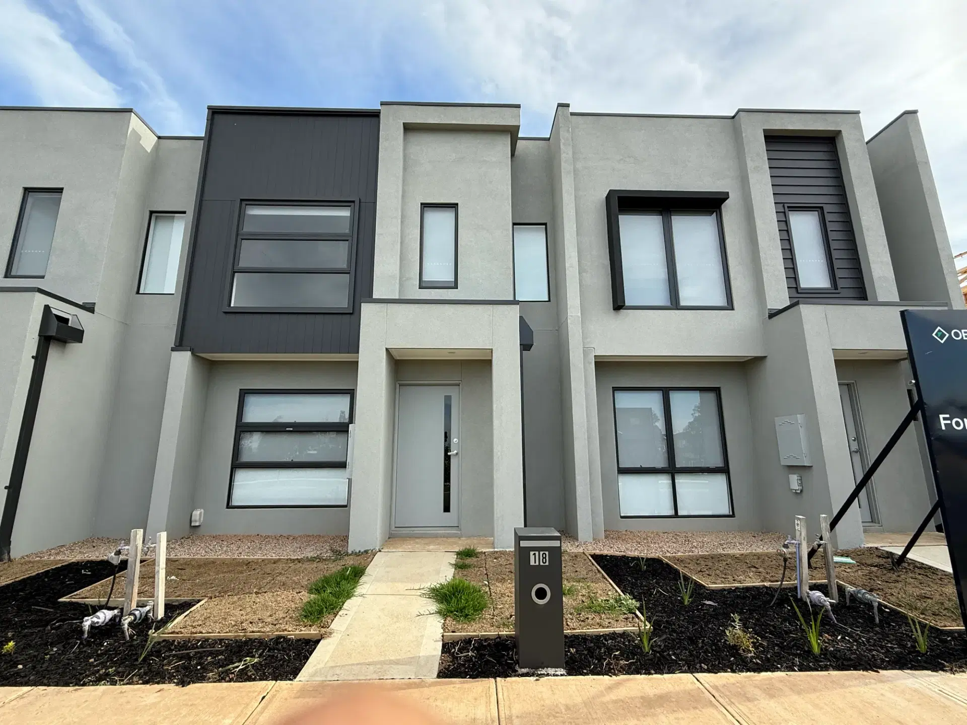 Street frontage of the Priya Street town homes in Werribee, rendered in grey and charcoal with landscaped garden beds